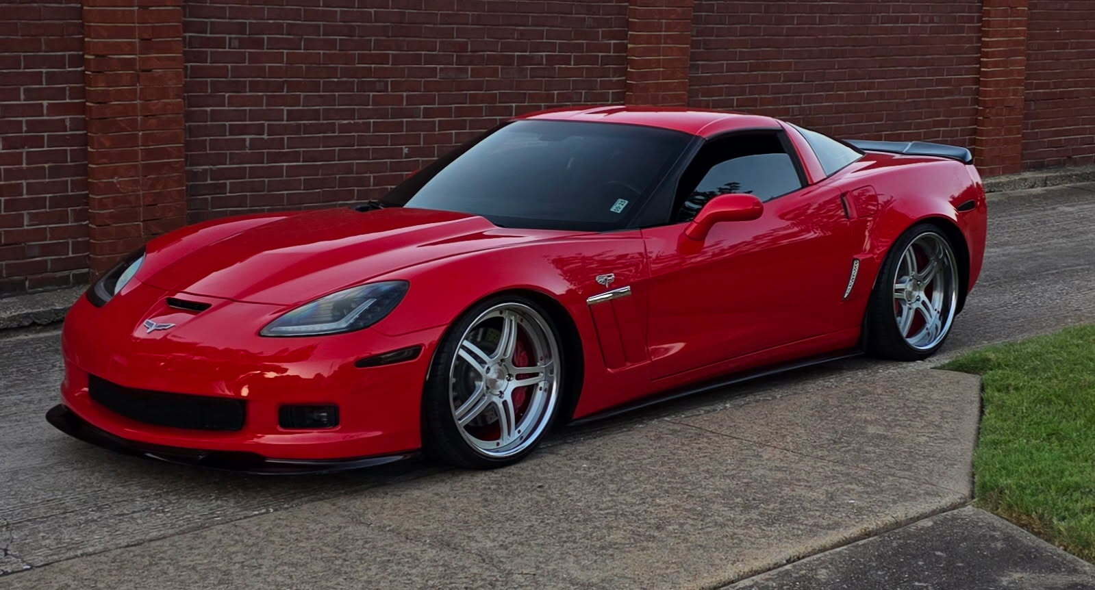 Red sports car parked on a driveway with a brick wall in the background