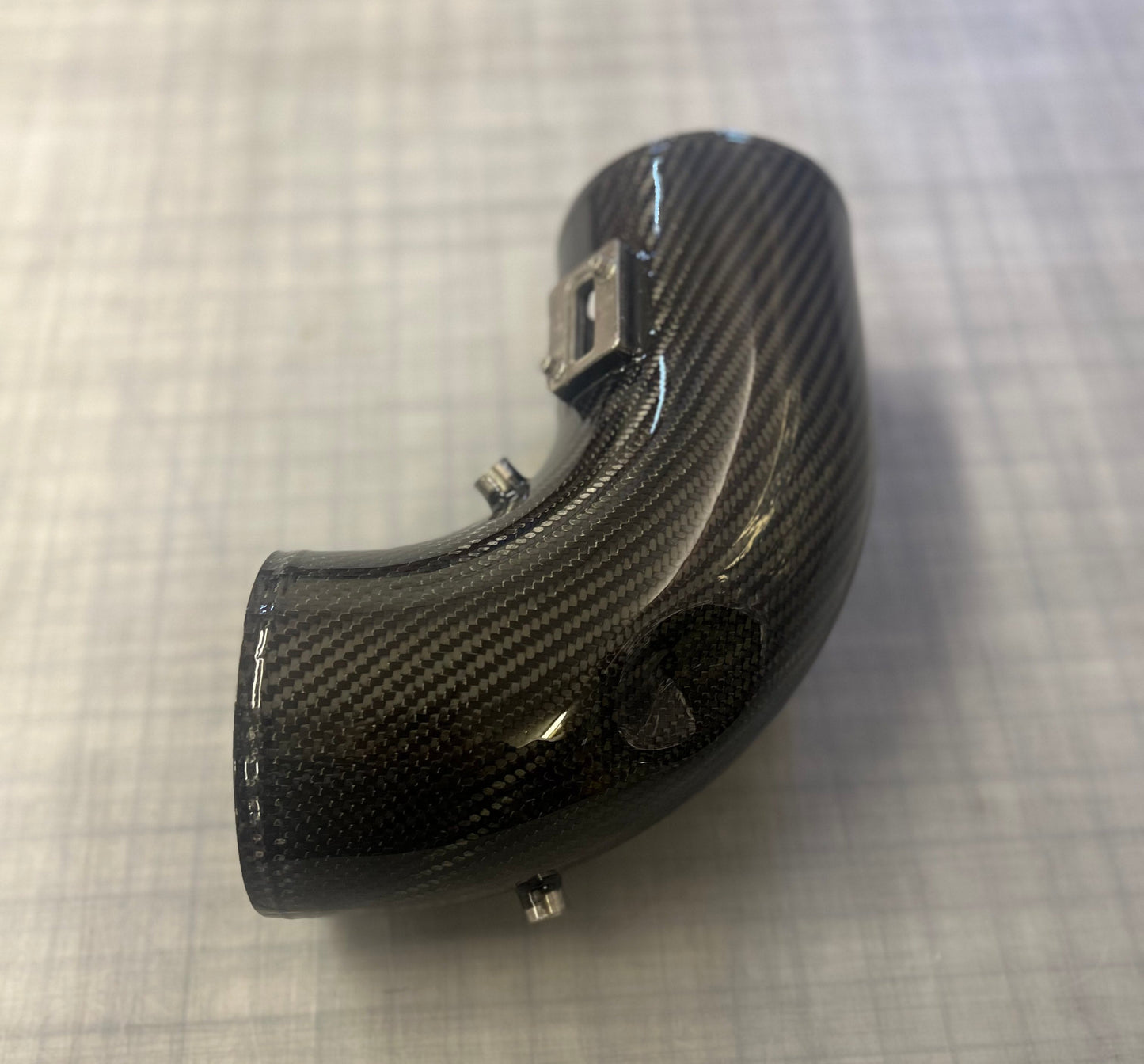 Carbon fiber motorcycle exhaust on a textured gray surface