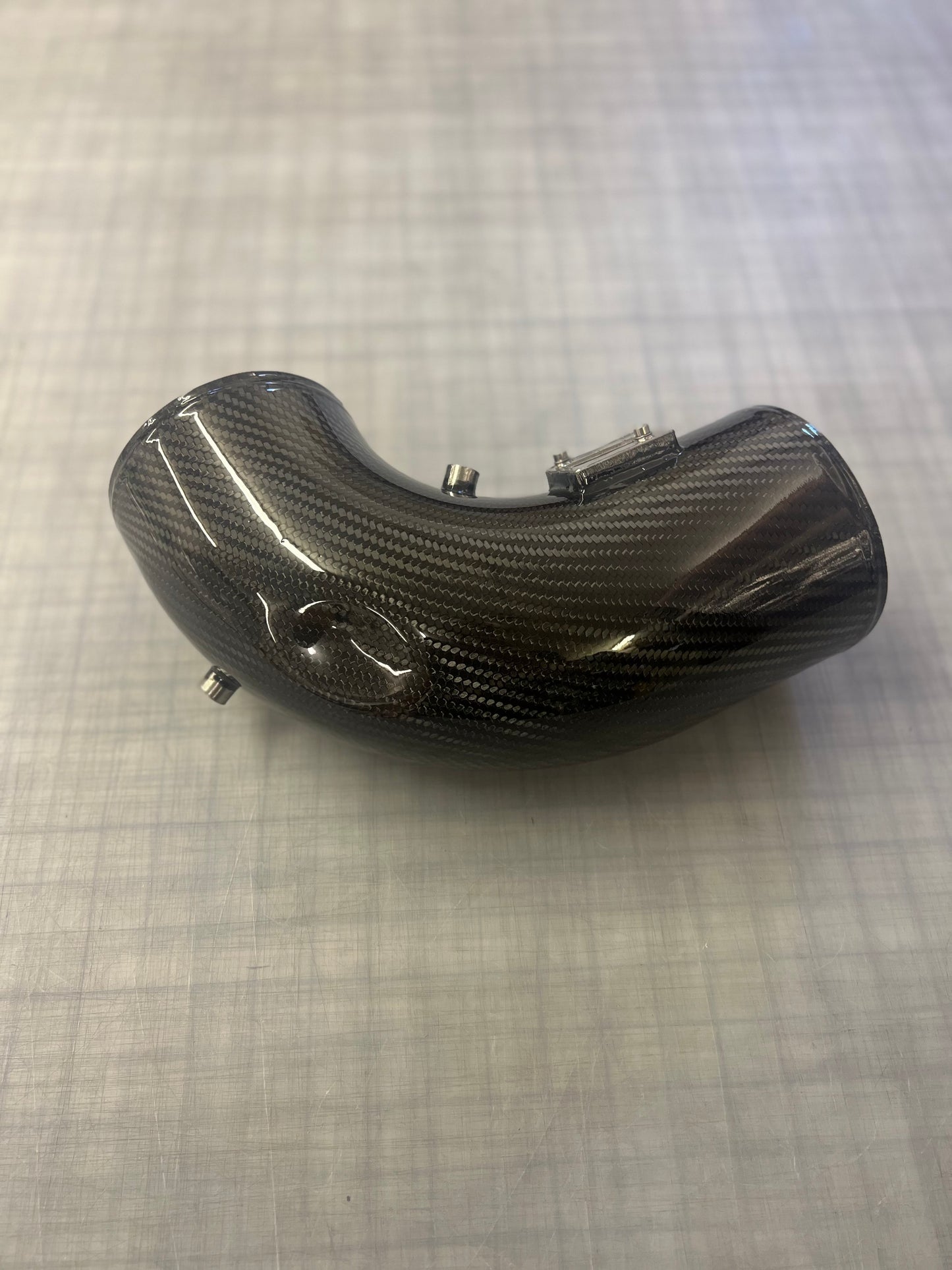 Carbon fiber motorcycle part on a textured gray surface
