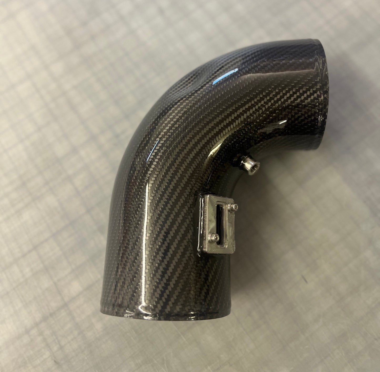 Carbon fiber air intake elbow on a textured gray background