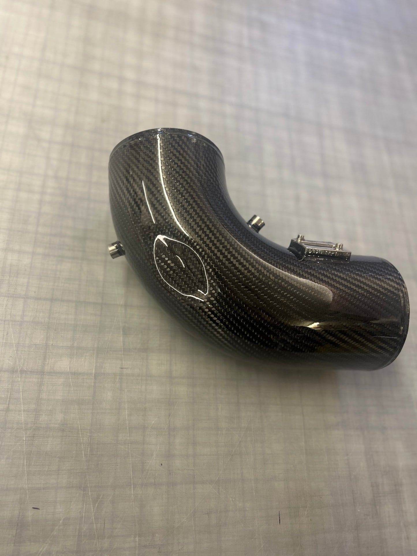 Carbon fiber exhaust pipe on a textured gray background