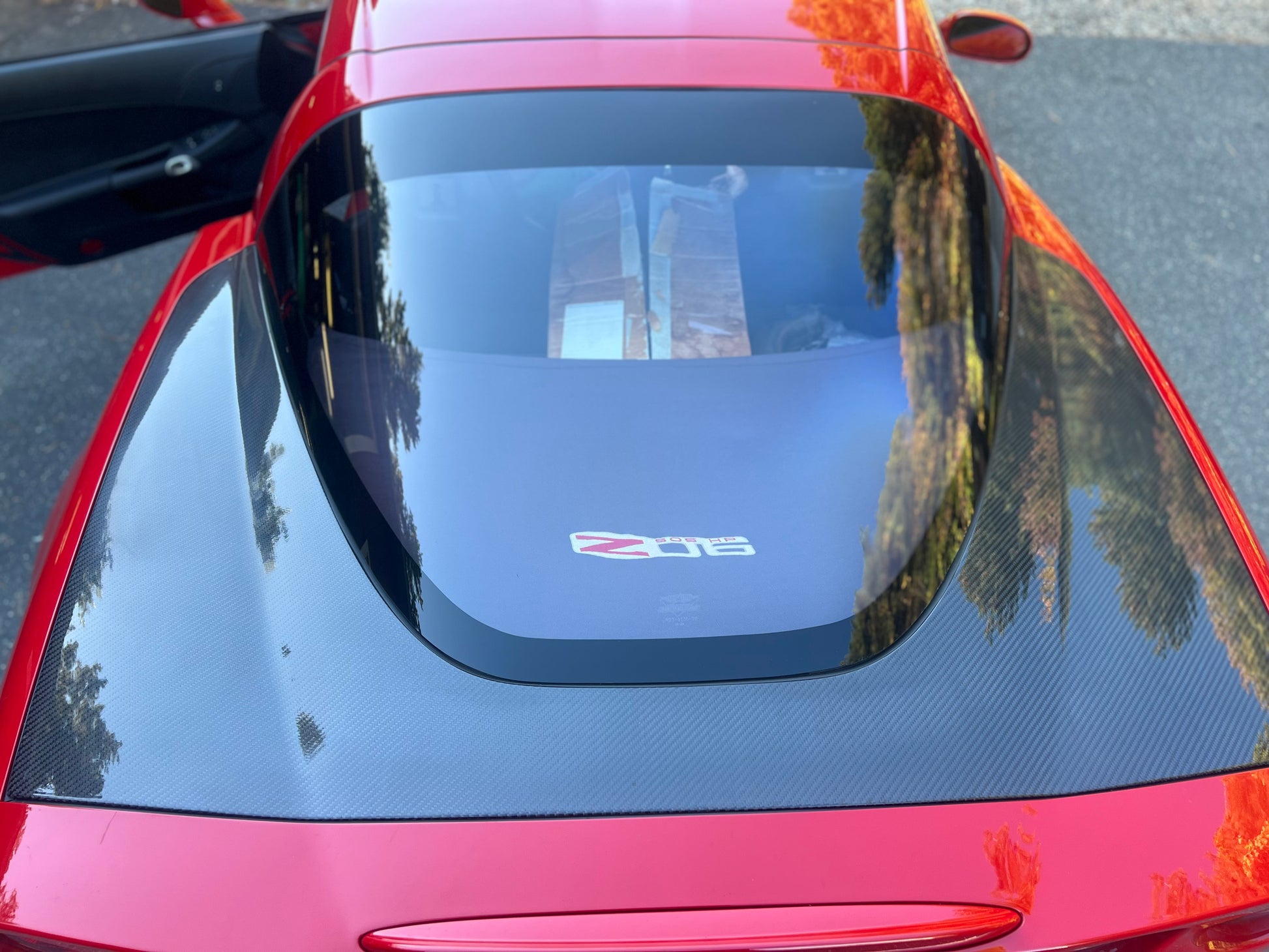 Red car with a sunshade on the windshield, reflecting palm trees and buildings.