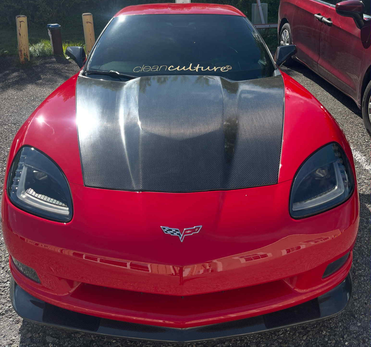 Red and black sports car with a visible Chevrolet logo on a gravel surface.