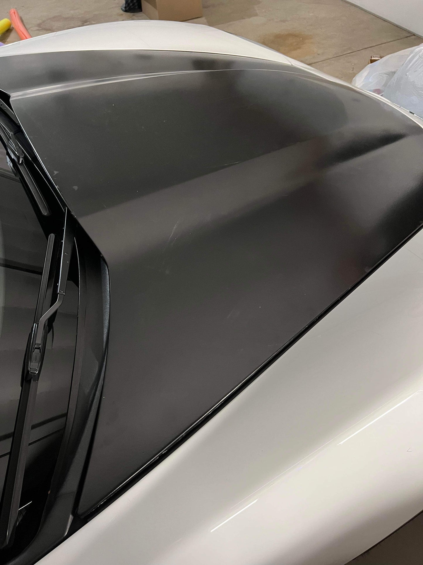 A black carbon fiber hood for a Corvette, showing the textured surface and fit on a vehicle.