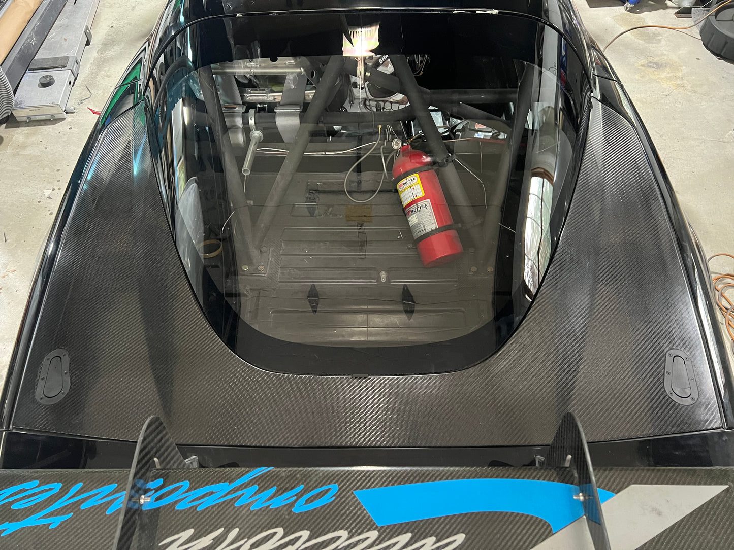 Carbon fiber hatch for a vehicle, showing the interior with a fire extinguisher mounted, indicating it is designed for a car like the C6 Corvette.