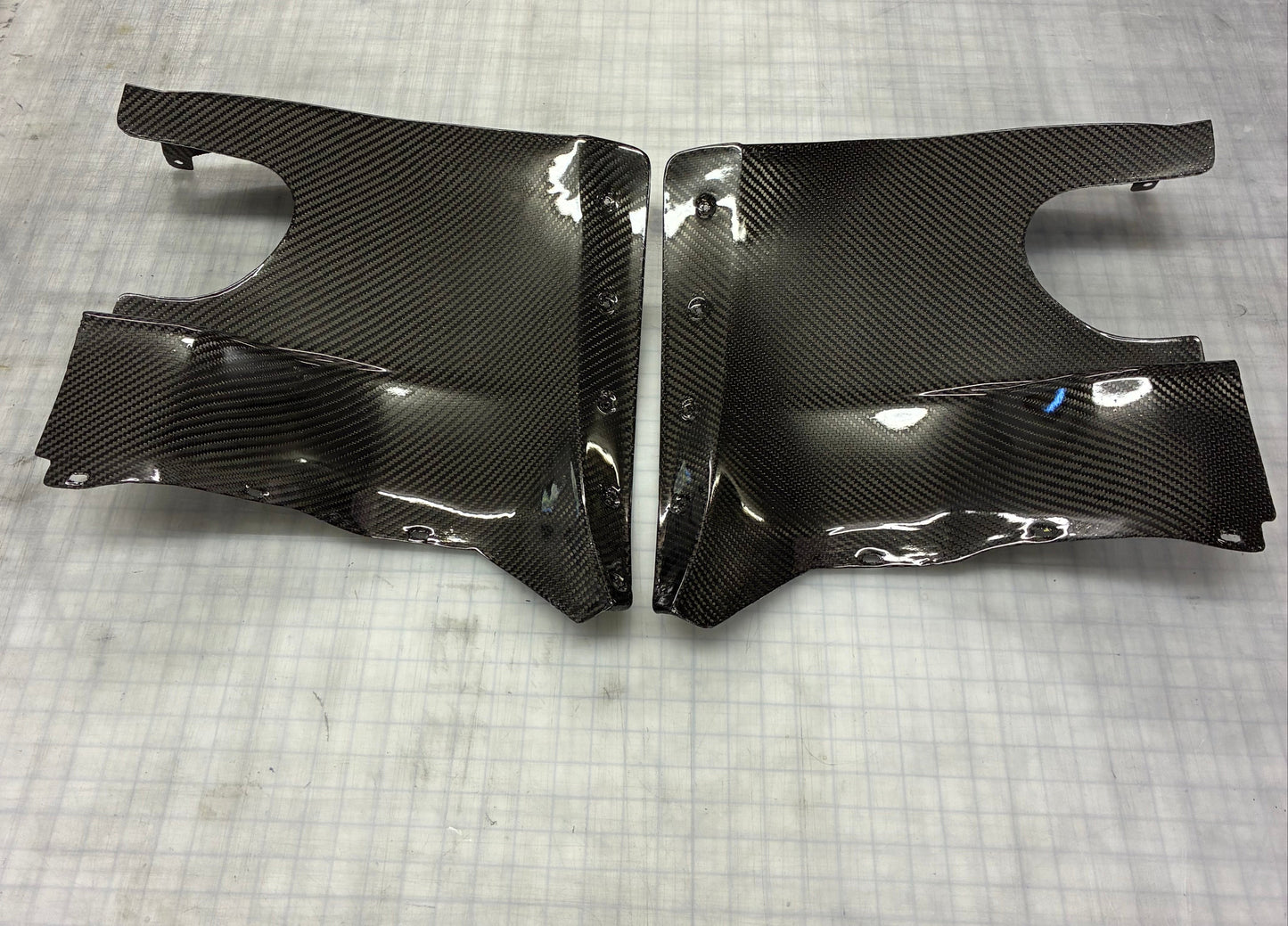 Carbon fiber car body panels on a textured gray surface