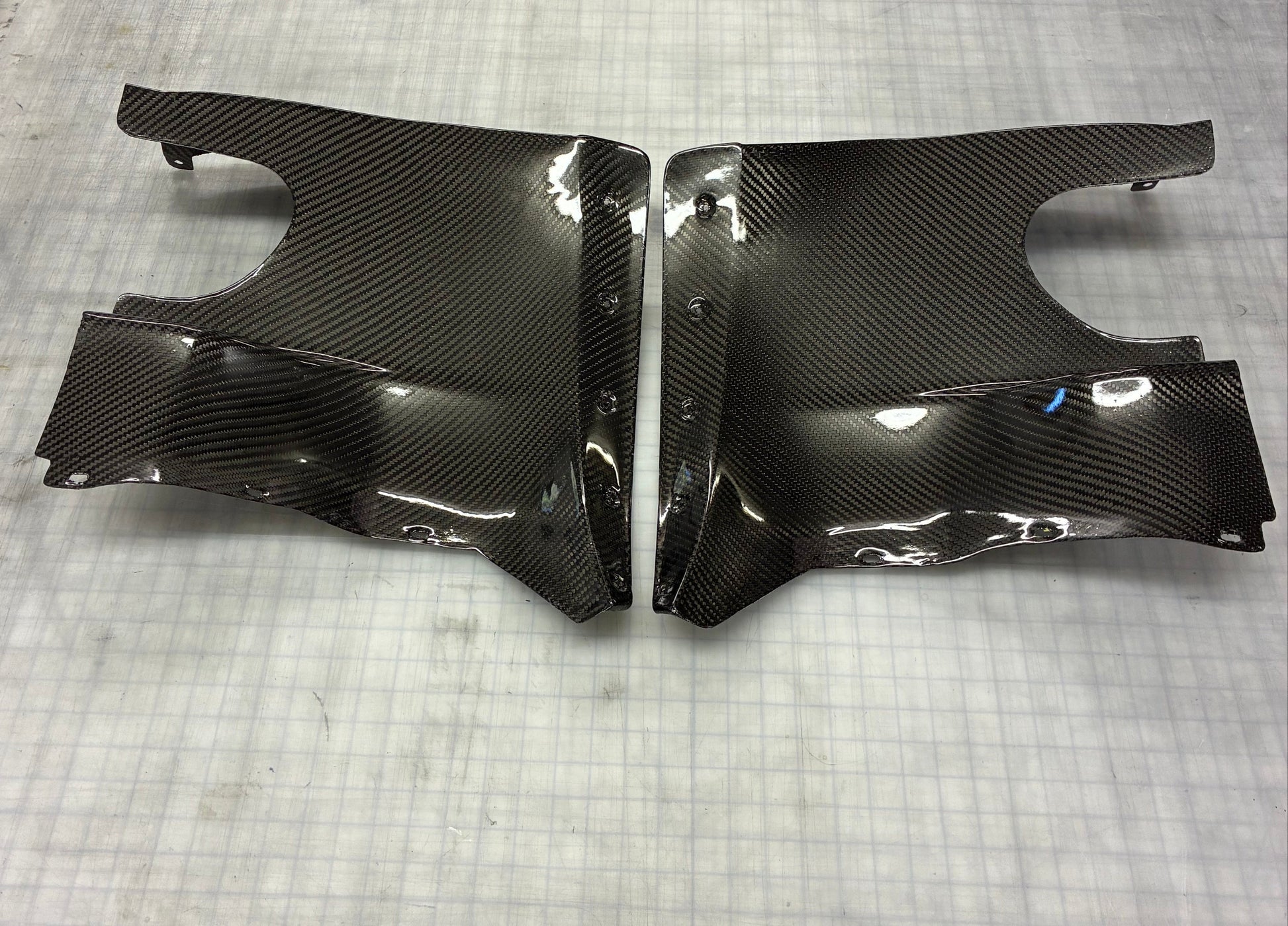 Carbon fiber car body panels on a textured gray surface