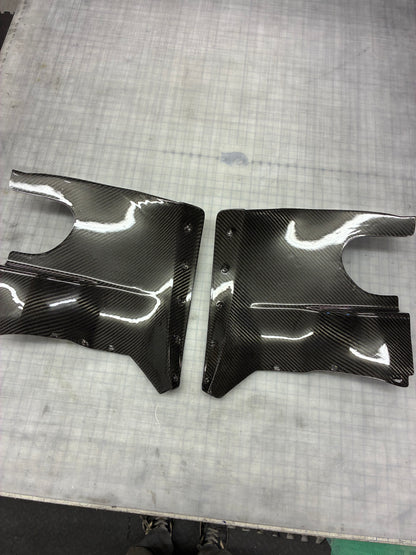 Two carbon fiber car parts on a textured surface