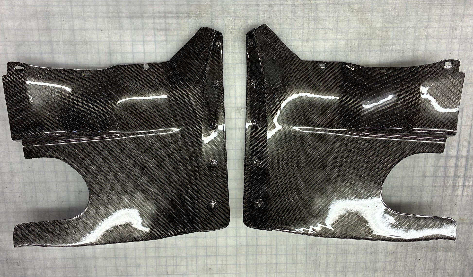 Two carbon fiber car parts on a checkered background