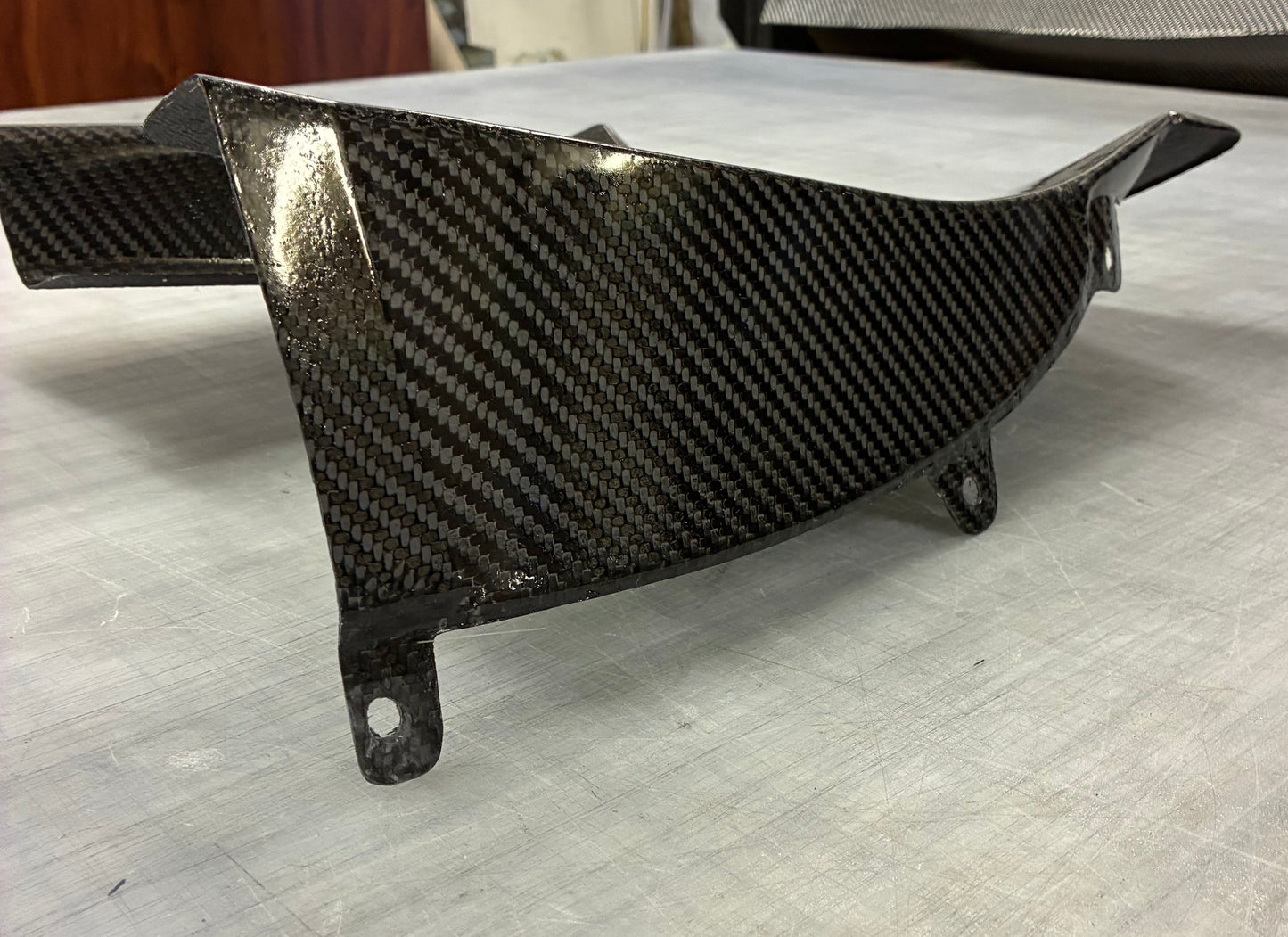 Carbon fiber panel on a white surface with a blurred background
