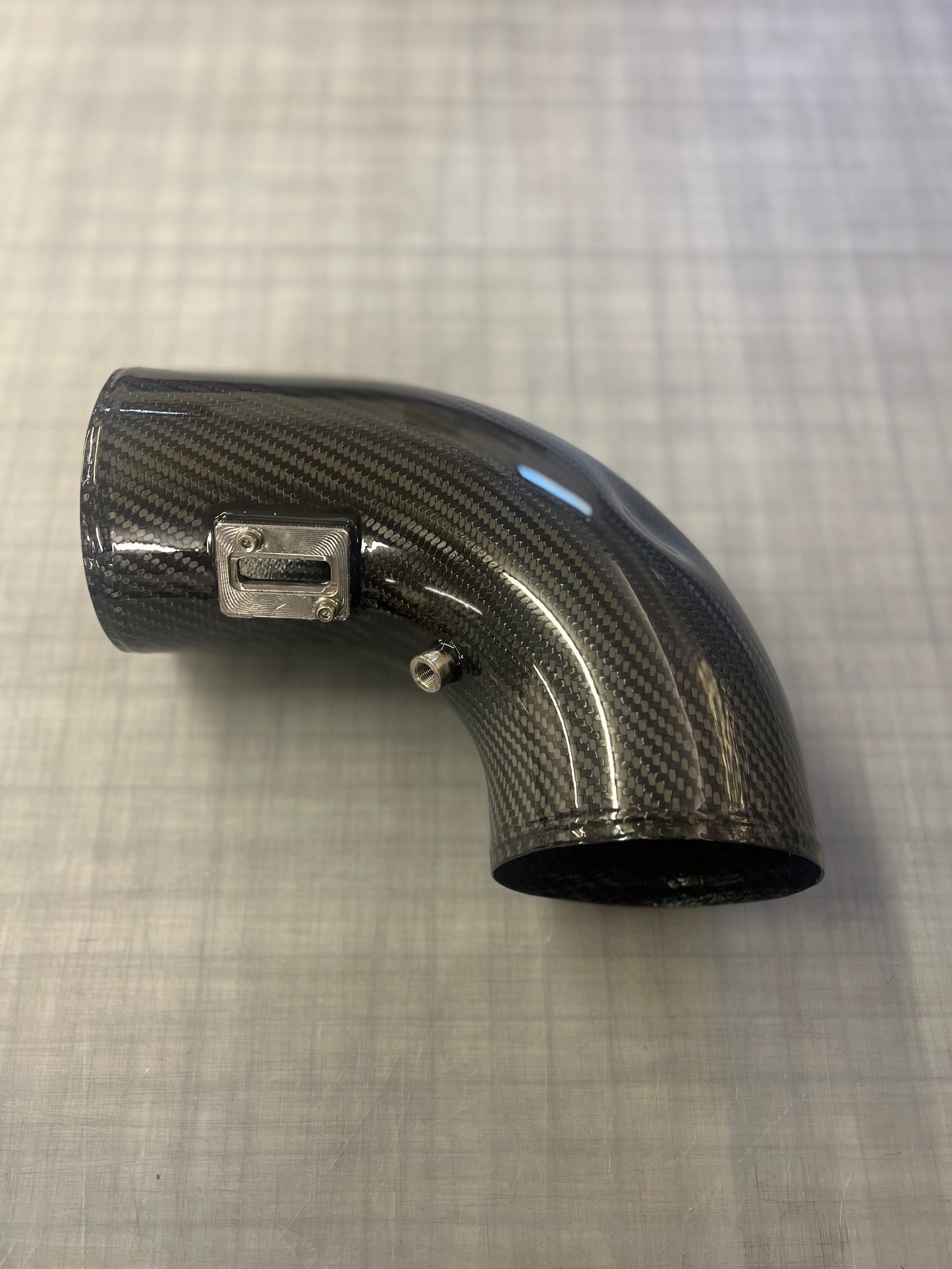 Carbon fiber elbow pipe on a textured gray background