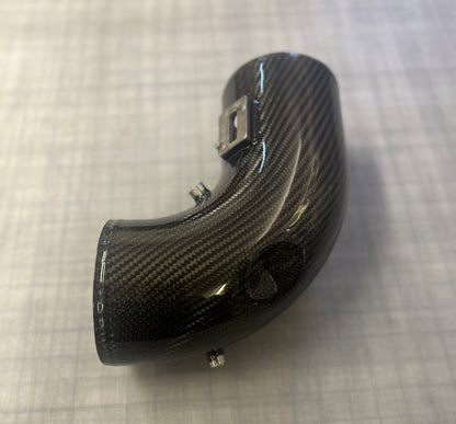 Carbon fiber motorcycle exhaust on a textured gray surface
