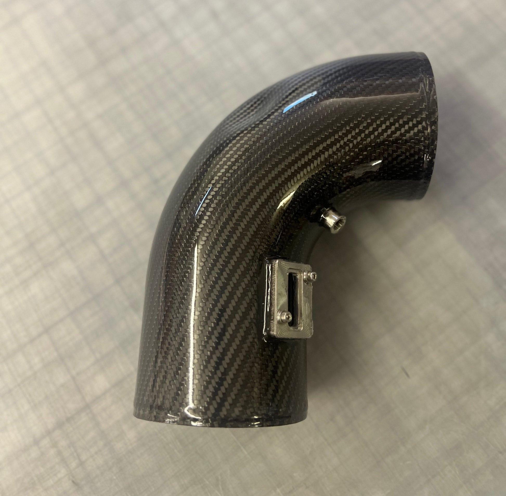 Carbon fiber air intake elbow on a textured gray background