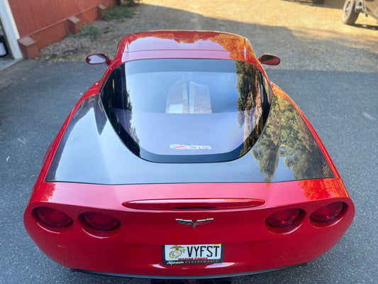 Red Corvette car with a visible license plate on a driveway.
