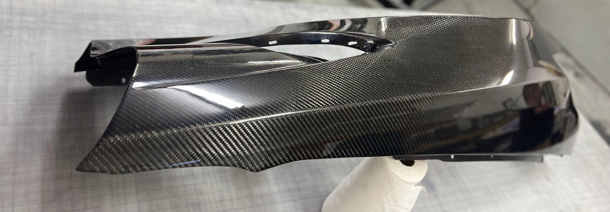 Carbon fiber car part on a gray surface with a blurred background