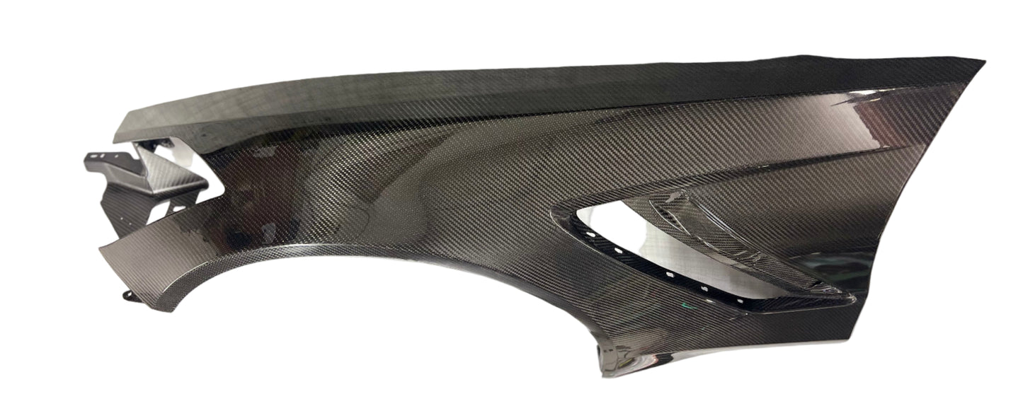 Carbon fiber car part on a white surface with a blurred background