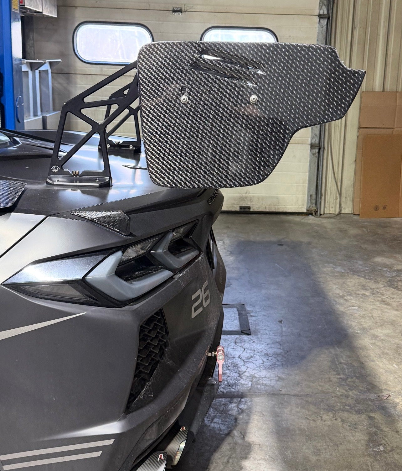Gray vehicle with a large black rear window in a garage setting